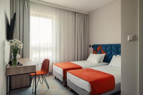 格但斯克雷比赫瓦Hotel Faros Gdansk Airport的酒店客房设有两张床、一张书桌和一个窗户。
