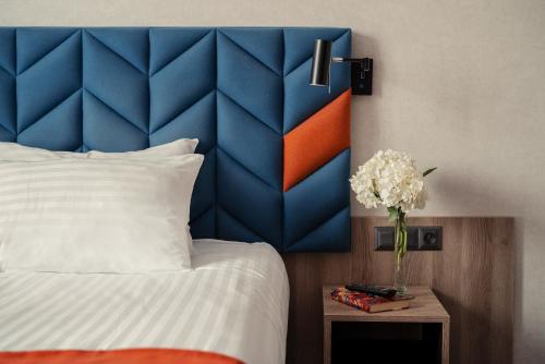 格但斯克雷比赫瓦Hotel Faros Gdansk Airport的一间卧室配有蓝色和橙色床头板和一张床
