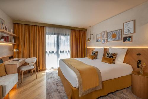 波尔多Hôtel Burdigala by Inwood Hotels的酒店客房设有一张大床和一张书桌。