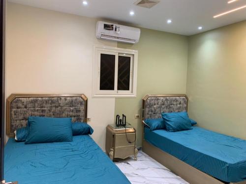 艾斯尤特شقه فندقيه الترا لوكس的一间卧室设有两张带蓝色床单的床和窗户。
