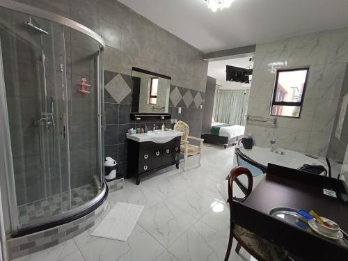 哈博罗内Manasseh Guesthouse的带淋浴、两个盥洗盆和淋浴的浴室。