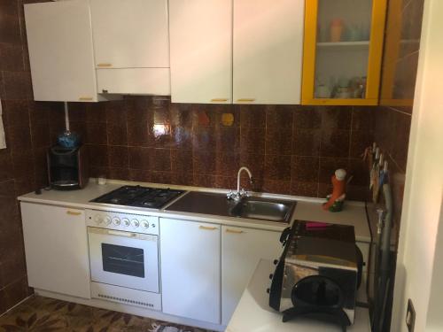 巴勒莫Residence Enrico的厨房配有白色橱柜、炉灶和水槽。