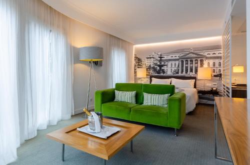 里斯本萨尔达尼亚酒店的客厅配有绿色沙发和床。