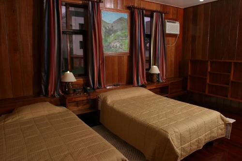 马卡埃Hotel Du Lac Macaé的一间卧室设有两张床和窗户。