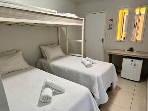 皮拉尼亚斯Pousada Lua Rosa的配有白色床单的酒店客房内的两张床
