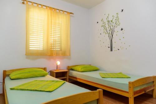 特罗吉尔Apartment in Okrug Gornji with sea view, air conditioning, WiFi, washing machine 5049-2的配有绿色枕头和窗户的客房内的两张床