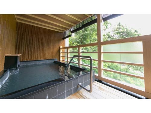 黑部市Unazuki Onsen Sanyanagitei - Vacation STAY 06440v的带大窗户的客房内的热水浴池