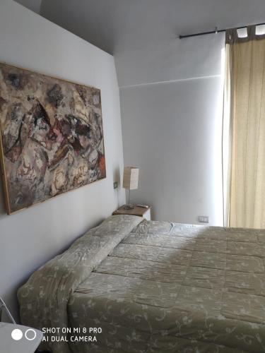 Minervino MurgeTaverna Garibaldi Casa Lucia的卧室配有一张床,墙上挂有绘画作品