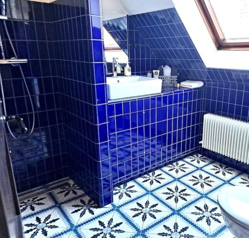 艾镇Maison Marcks Champagne的蓝色瓷砖浴室设有浴缸和水槽