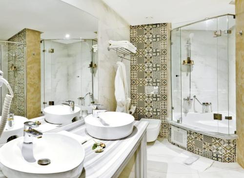 非斯Fes Heritage Boutique luxury Hotel的浴室配有2个盥洗盆、淋浴和浴缸。