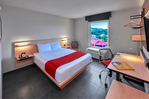 坦皮科坦皮科城市快捷酒店的配有一张床、一张书桌和一扇窗户的酒店客房