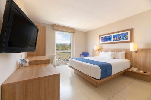 圣何塞City Express by Marriott San José Costa Rica的配有一张床和一台平面电视的酒店客房