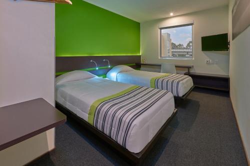 普埃布拉City Express Junior by Marriott Puebla FINSA的一间设有两张床和绿色墙壁的客房
