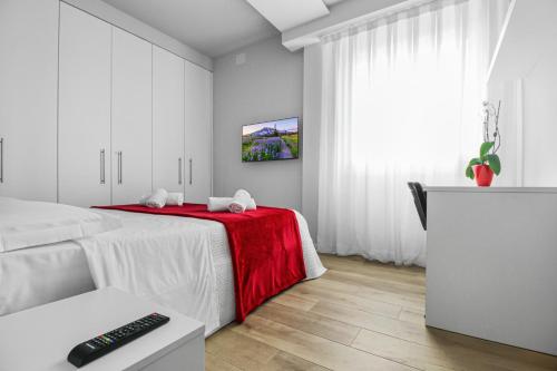 维罗纳Appartamento VITTORIA的白色卧室配有一张带红色毯子的床
