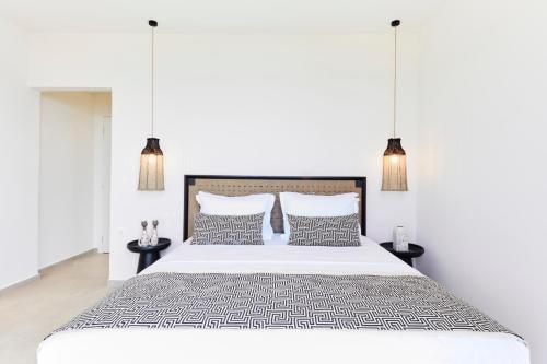 斯基亚索斯镇Skiathos Ammos Luxury Apartments的白色卧室配有一张大床和两张桌子