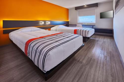 圣路易斯波托西City Express Junior by Marriott San Luis Potosi Carranza的橙色墙壁客房的两张床