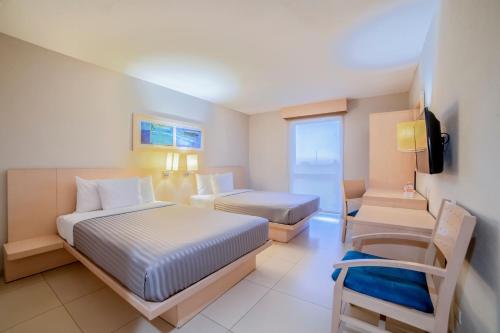 卡门城卡门城市快捷酒店的酒店客房,配有两张床和椅子