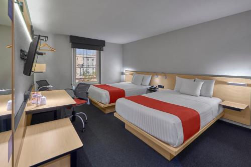 提华纳提华纳里约城市快捷酒店的酒店客房配有两张床和一张书桌
