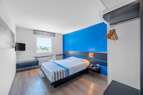 梅里达City Express Junior by Marriott Merida Altabrisa的蓝色的卧室设有床和窗户