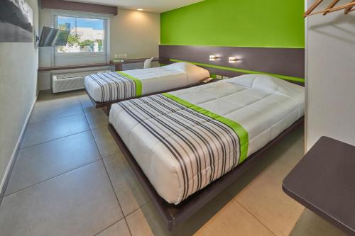 坎昆City Express Junior by Marriott Cancun的绿墙客房的两张床