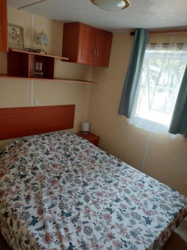 Orgnac-lʼAvenMobile home的一间卧室配有一张带花卉床罩的床和窗户。