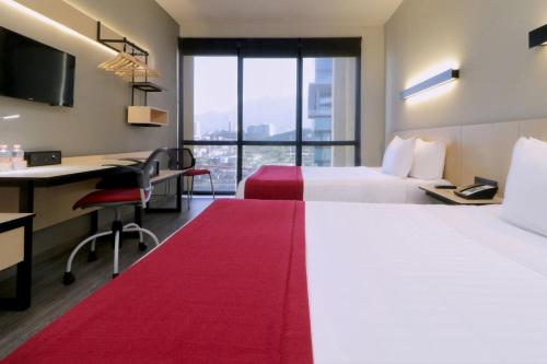 蒙特雷City Express Plus by Marriott Monterrey Galerías的酒店客房配有两张床和一张书桌