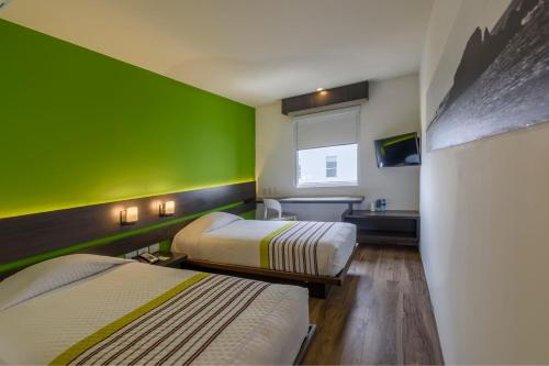 波哥大City Express Junior by Marriott Bogota Aeropuerto的一间设有两张床和绿色墙壁的客房
