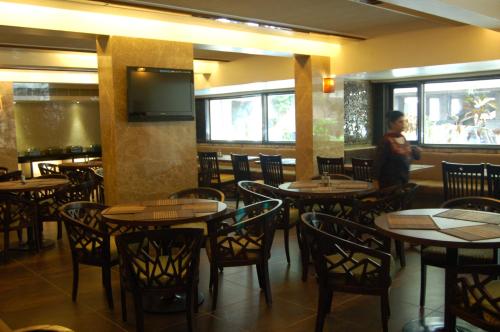 艾哈迈达巴德总统精品酒店的一间带桌椅和电视的用餐室