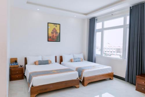 莲三Khách sạn Hoàng My的一间卧室设有两张床和窗户。