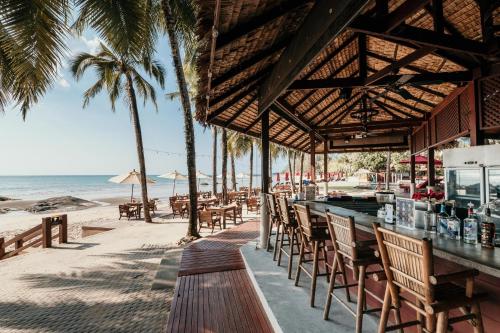 蔻立Khaolak Laguna Resort的海滩上的酒吧,种植了棕榈树,享有海景