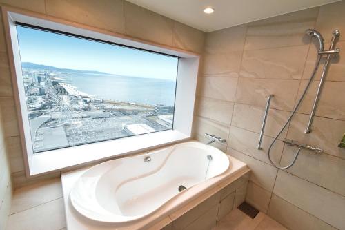 泉佐野Odysis Suites Osaka Airport Hotel的带浴缸的浴室和大窗户