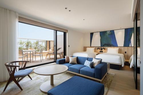 淡路Fairfield by Marriott Hyogo Awaji Higashiura的酒店客房带蓝色的沙发以及一间卧室