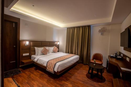班加罗尔Golden Fortune Hotel的酒店客房设有一张大床和一张书桌。