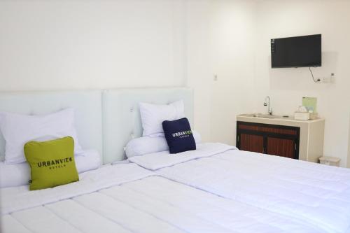 MarosUrbanview Hotel Eropa Maros Near Sultan Hasanuddin Airport的卧室配有白色的床和2个枕头