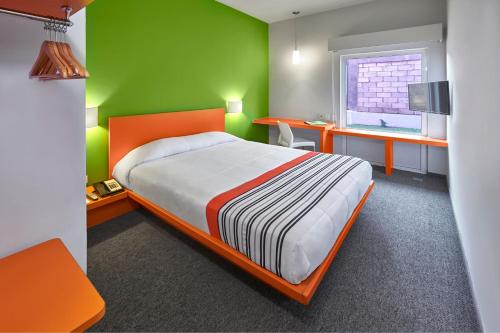 瓜达拉哈拉City Express Junior by Marriott Guadalajara Periferico Sur的一间卧室设有一张床和绿色的墙壁