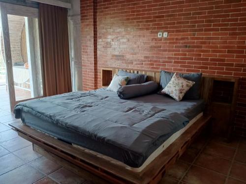 外南梦Pondok isoke bunggalow的砖墙房间的一个床位
