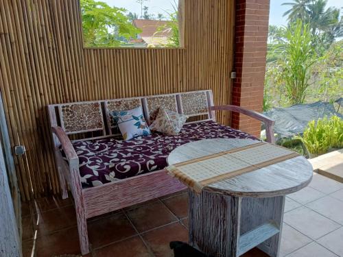 外南梦Pondok isoke bunggalow的门廊上带枕头的长凳和桌子