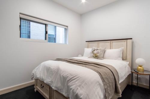 悉尼Eggie's Nest - Luxury City Apartment的白色卧室设有一张大床和窗户
