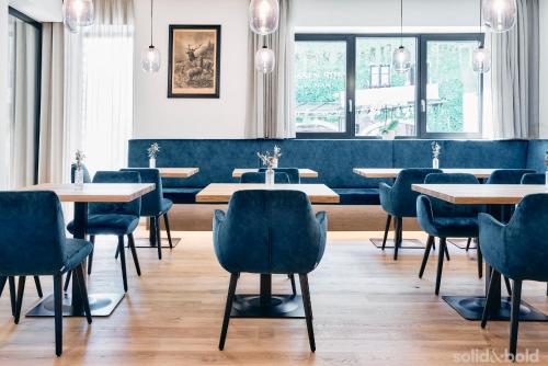 圣沃尔夫冈Hotel Weisser Hirsch的餐厅设有蓝色的椅子和桌子以及窗户。