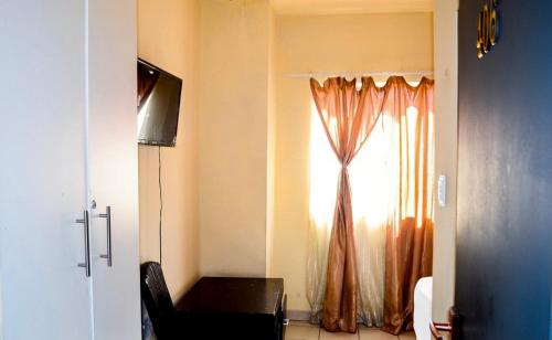 约翰内斯堡Asmara Hotel的客房设有带椅子的窗户和电视。