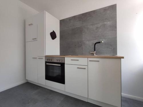 比勒费尔德'BRIGHT 201' Moderne, helle Wohnung in BI Zentrum, 400 m bis Lokschuppen, Smart-TV, WLAN的厨房配有白色橱柜和水槽