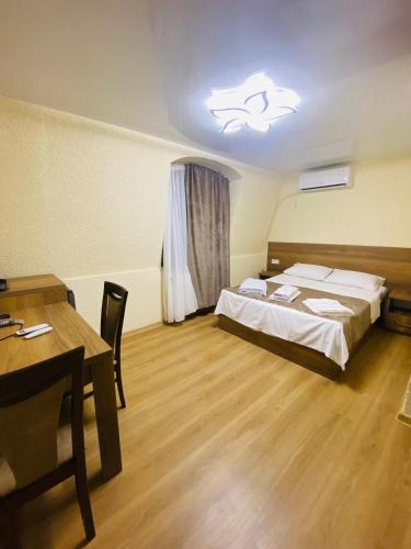 库塔伊西HOTEL SUNRISE的一间卧室配有一张床、一张桌子和一盏灯