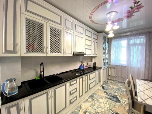 TürkistanЯсауи аппартамент的厨房配有白色橱柜和黑色台面