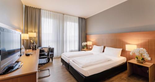 科隆PLAZA Premium Köln的酒店客房配有一张床、一张书桌和一台电视。