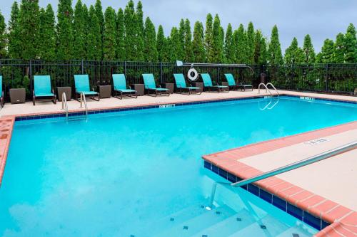 亨茨维尔亨茨维尔公寓式酒店的一个带蓝色躺椅的游泳池,靠近围栏