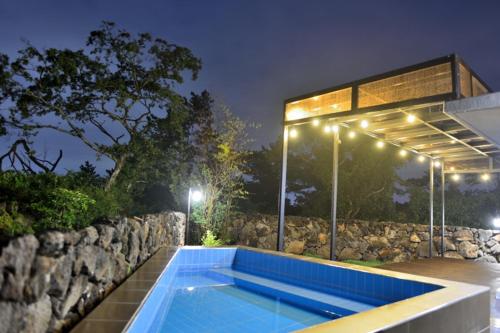 济州市Hyeopjae Claire de lune的一座带灯光的建筑前的游泳池