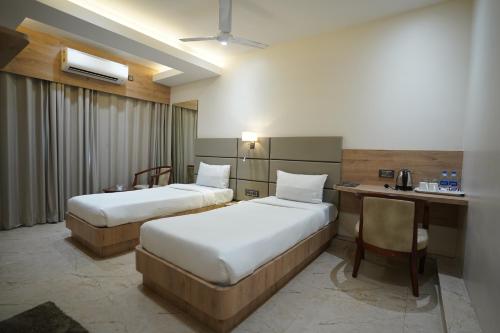 丹巴德HOTEL THE VENUE的酒店客房配有两张床和一张书桌