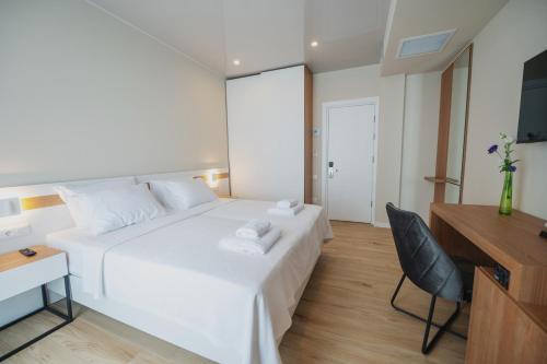 乌雷基Ritsa Resort的一张白色的床,房间配有一张桌子和一把椅子