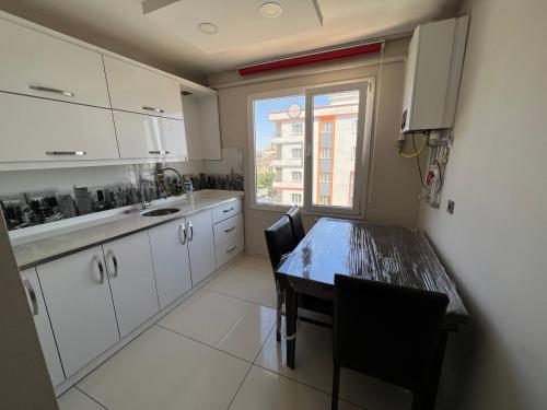 MidyatXANTHOS APART HOTEL Midyat Merkezde的厨房配有白色橱柜、桌子和窗户。