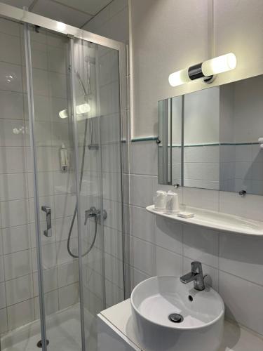 安纳马斯Hôtel Du Centre Annemasse的带淋浴、盥洗盆和镜子的浴室